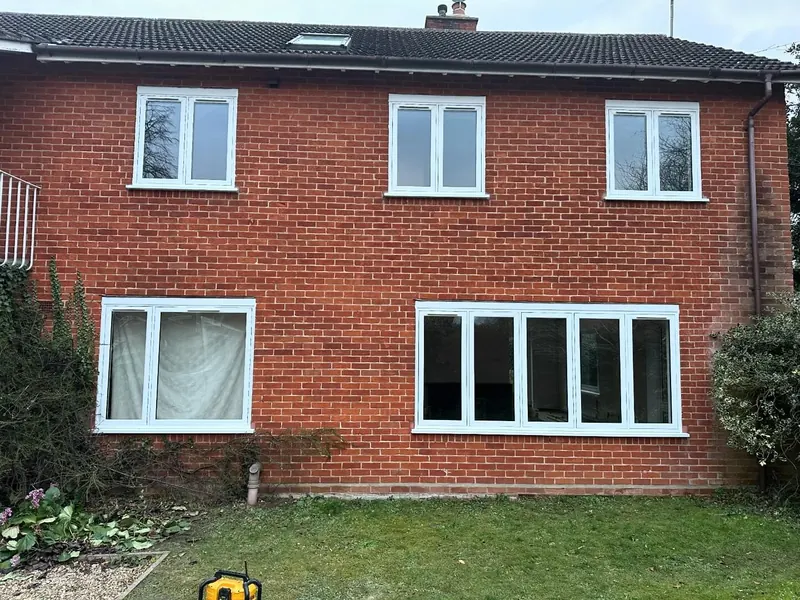 New white uPVC windows installed across the rear of a detached brick house